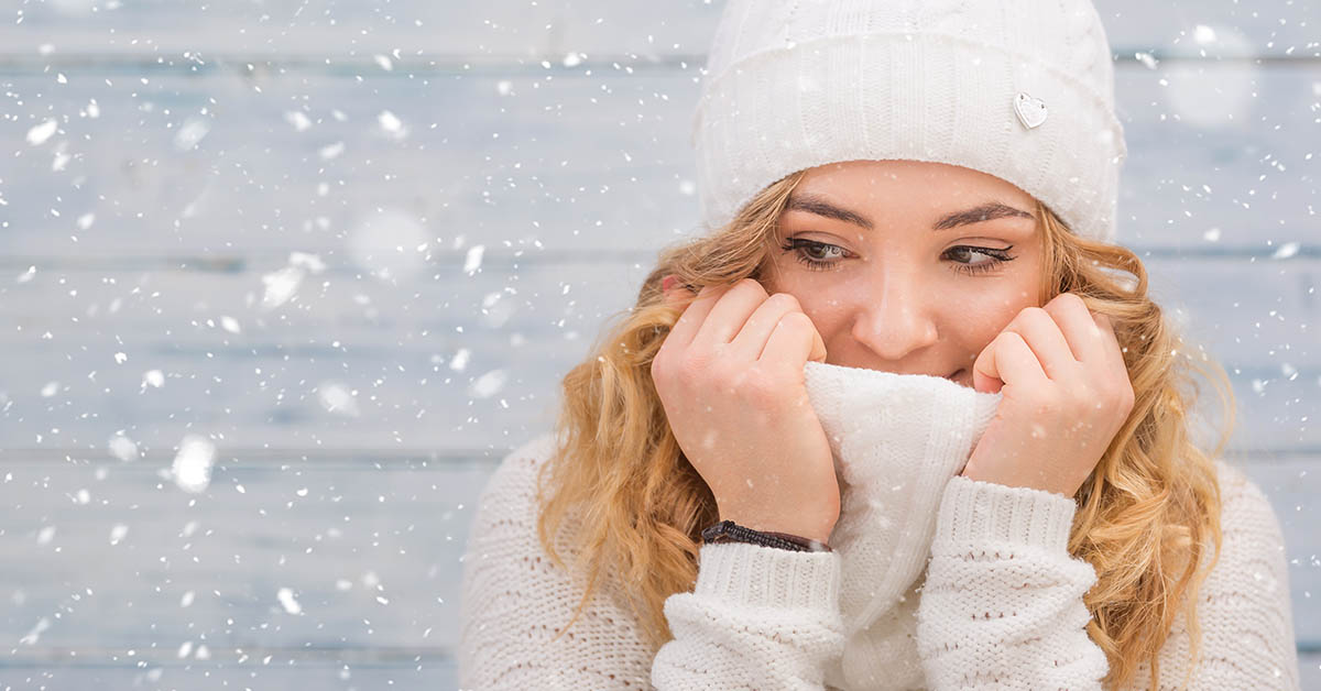 Woman wearing hat and sweater in the snow.