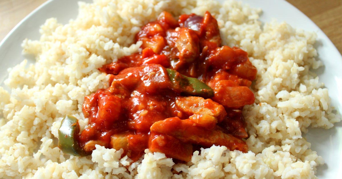 A plate of shrimp stir fry on a bed of brown rice.